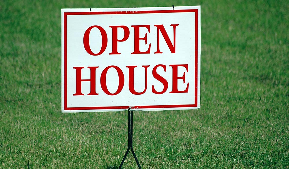 An open house sign in a yard illustrating the risks of selling your home without a realtor